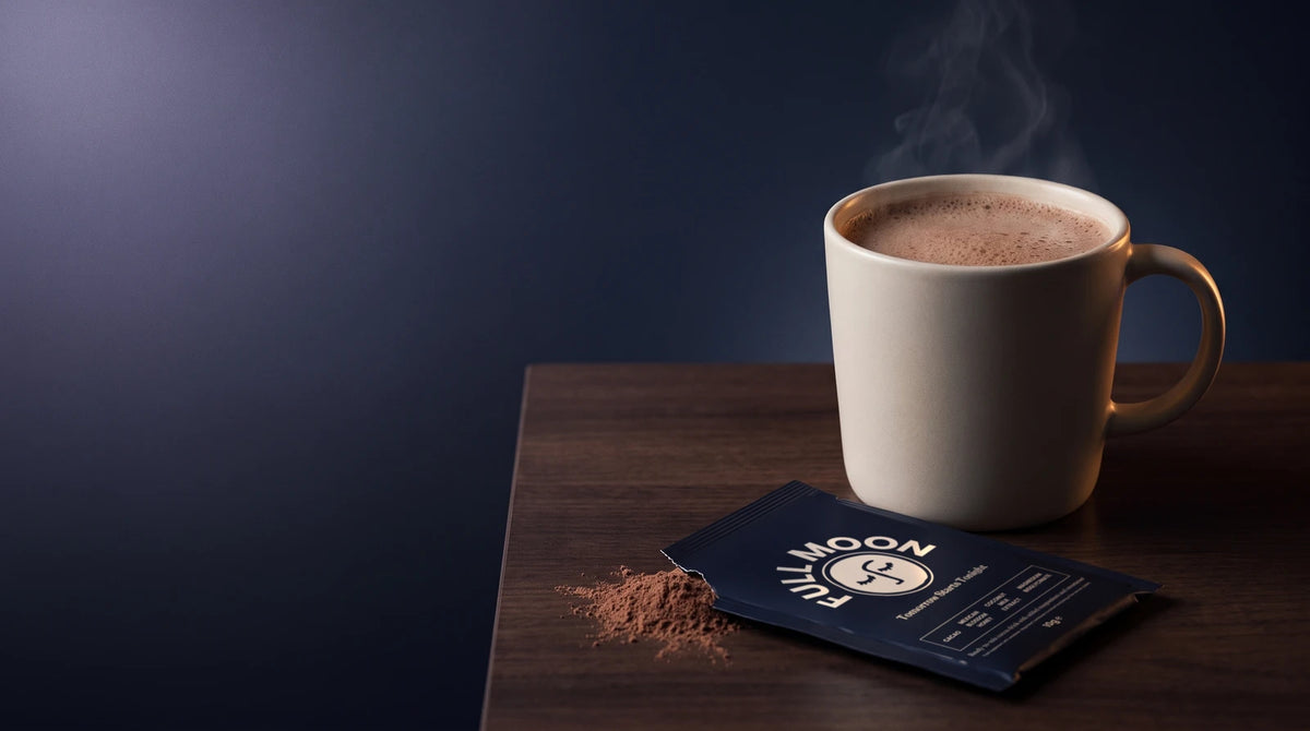 A Full Moon sachet, torn open, beside a mug of hot cacao on a dark walnut surface